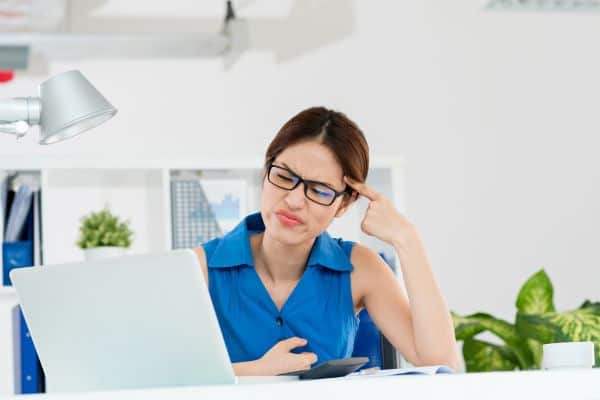 Thinking woman looking at computer monitor