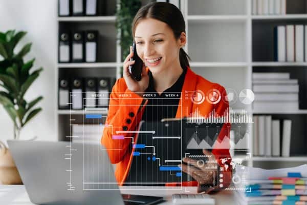 Woman on phone looking at computer with virtual data schematic